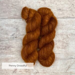 Two skeins of rusty brown mohair and silk lace yarn on pale wood background