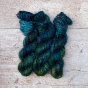 Three skeins of plump DK wool in dark blues, emeralds and lime