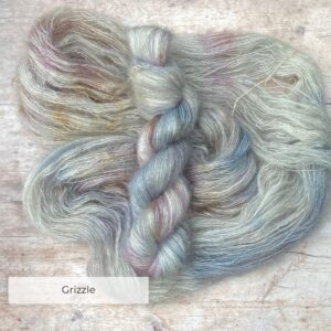 Two skeins Mohair Silk lace weight yarn in soft warm grey, speckled with brown on pale wood surface