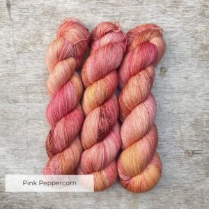 Three skeins of Classic Sock in peach, coral and mulberry freckled with terracotta and gold
