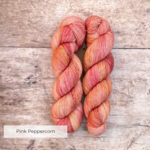 Two skeins classic sock in pinks and coral on pale wood surface