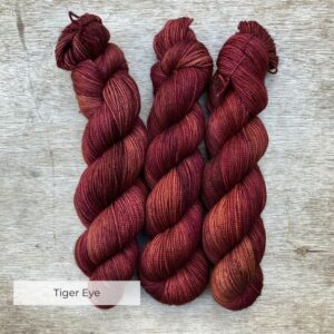 Three skeins of yarn a golden burgundy colour