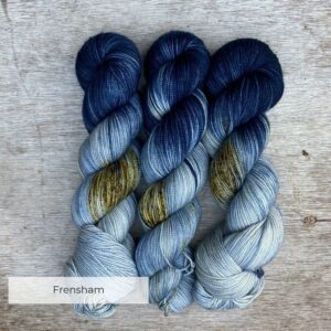 Three skeins of sock yarn in a pale speckled blue and a dark blue end