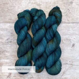 Three skeins classic sock in mid to dark blue with orange variegation on pale wood surface