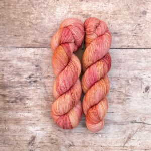 Two skeins classic sock in pinks and coral on pale wood surface