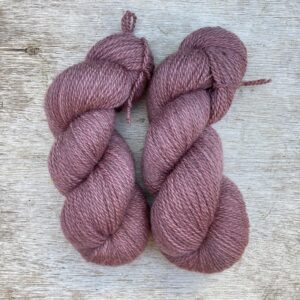 Two skeins of a soft rose yarn on a wooden background