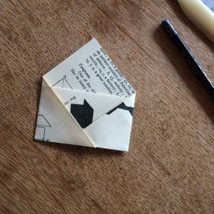 A paper envelope made from an old book page on a wooden table