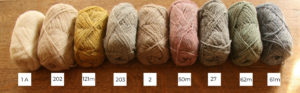 Nine balls of Shetland wool lined up in a row from light to dark