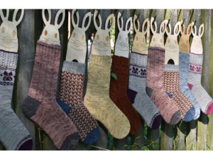 A row of bunny blockers clothed in many different socks all hanging up on a garden fence