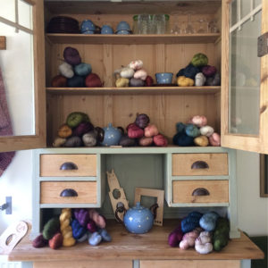 A close up of a kitchen dresser with doors open showing piles of wool