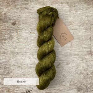 A single skein of deep moss green yarn on a wood background