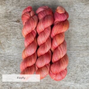Three skeins of soft merino and mohair yarn in a deep coral and pink