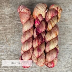 Three skeins of merino mohair yarn in a creamy yellow speckled with dark red and pinks