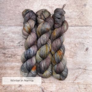 Three skeins of Merino Floof in browns, dark blues, plum and gold