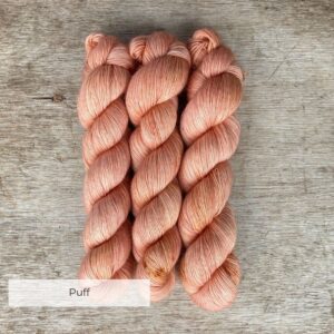 Three skeins of soft coral pink merino and mohair yarn with faint yellow speckles
