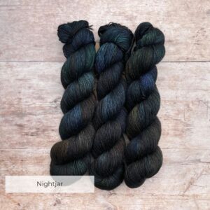 Three skeins of Merino Floof in deep greens, inky blues and rust
