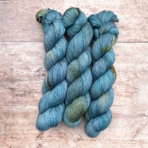 Three skeins of Merino Floof in mid denim blue with golden splashes