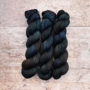 Three skeins of Merino Floof in deep greens, inky blues and rust