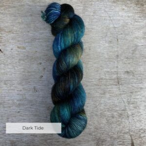 A single skein of yarn dyed with splashes of navy, emerald and gold