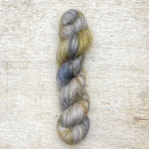 A single skein of fluffy mohair in greys and golds