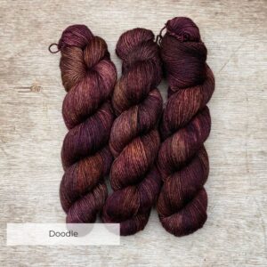 three skeins of yarn in brown, dusty pink and bronze