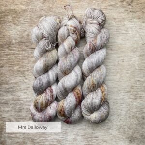 Three skeins of soft grey yarn speckled with ochre, plum and brown