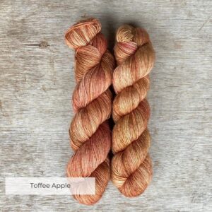 Two skeins of silky yarn in a warm yellow splashed with coral and toffee