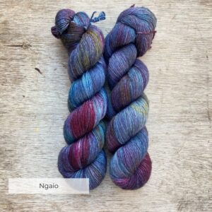 Two skeins of yarn in blues and green with splashes of dark purple and pink