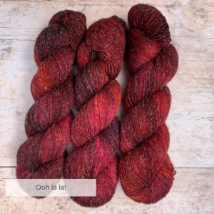 Three skeins of Merino and linen yarn in a rich red and dark pink