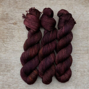 three skeins of yarn in brown, dusty pink and bronze