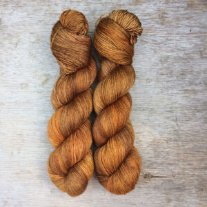 Two skeins of semi solid sock yarn that have been dyed in shades of toffee