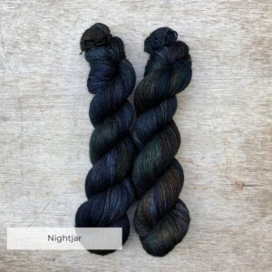 Two skeins of inky blue yarn with splashes of bottle green and rust