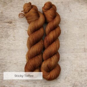 Two skeins of semi solid sock yarn that have been dyed in shades of toffee