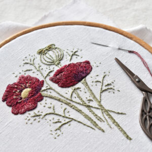An embroidery of poppies in a ring with some black scissors