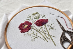 A flower embroidery on white linen in a wooden embroidery hoop