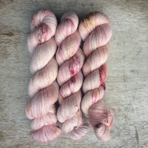 The skeins of fluffy pink yarn speckled in plums and gold