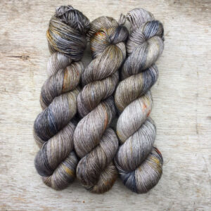 There hanks of silky yarn blue and gold splashes on a light brown base