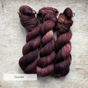 Three skeins of yarn in brown, dusty pink and bronze