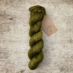 A single skein of deep moss green yarn on a wood background