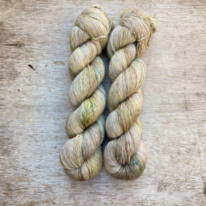 Two skeins of yarn in a neutral stone splashed with moss green