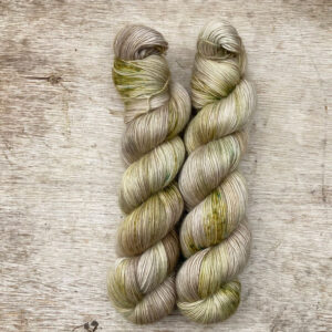 Two skeins of yarn in a neutral stone splashed with moss green