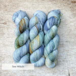 Three skeins of sock yarn in shades of blue, light grey and gold