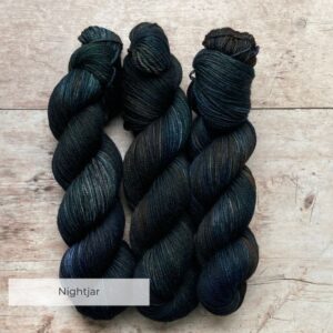 Three skeins of Plump DK in dark blue/green with splashes of brown and rust
