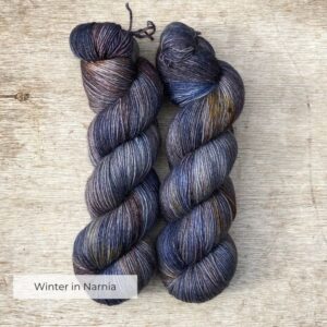 Two hanks of yarn in shades of blue, brown, gold and plum