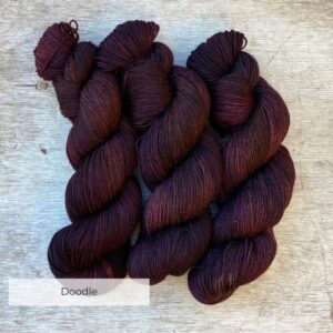 three skeins of yarn in brown, dusty pink and bronze