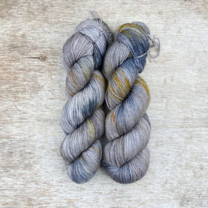 Two hanks of yarn blue and gold splashes on a light brown base