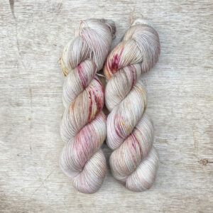 Two skeins of a mohair blend sock yarn in pinks, burgundy and gold