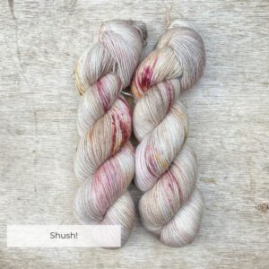 Two skeins of a mohair blend sock yarn in pinks, burgundy and gold