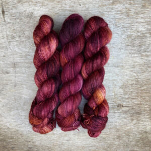 Three skeins of soft merino & mohair yarn in shades of pink, plum and orange