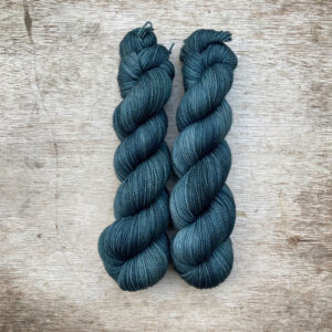 Two skeins of yarn in dark petrol blue green
